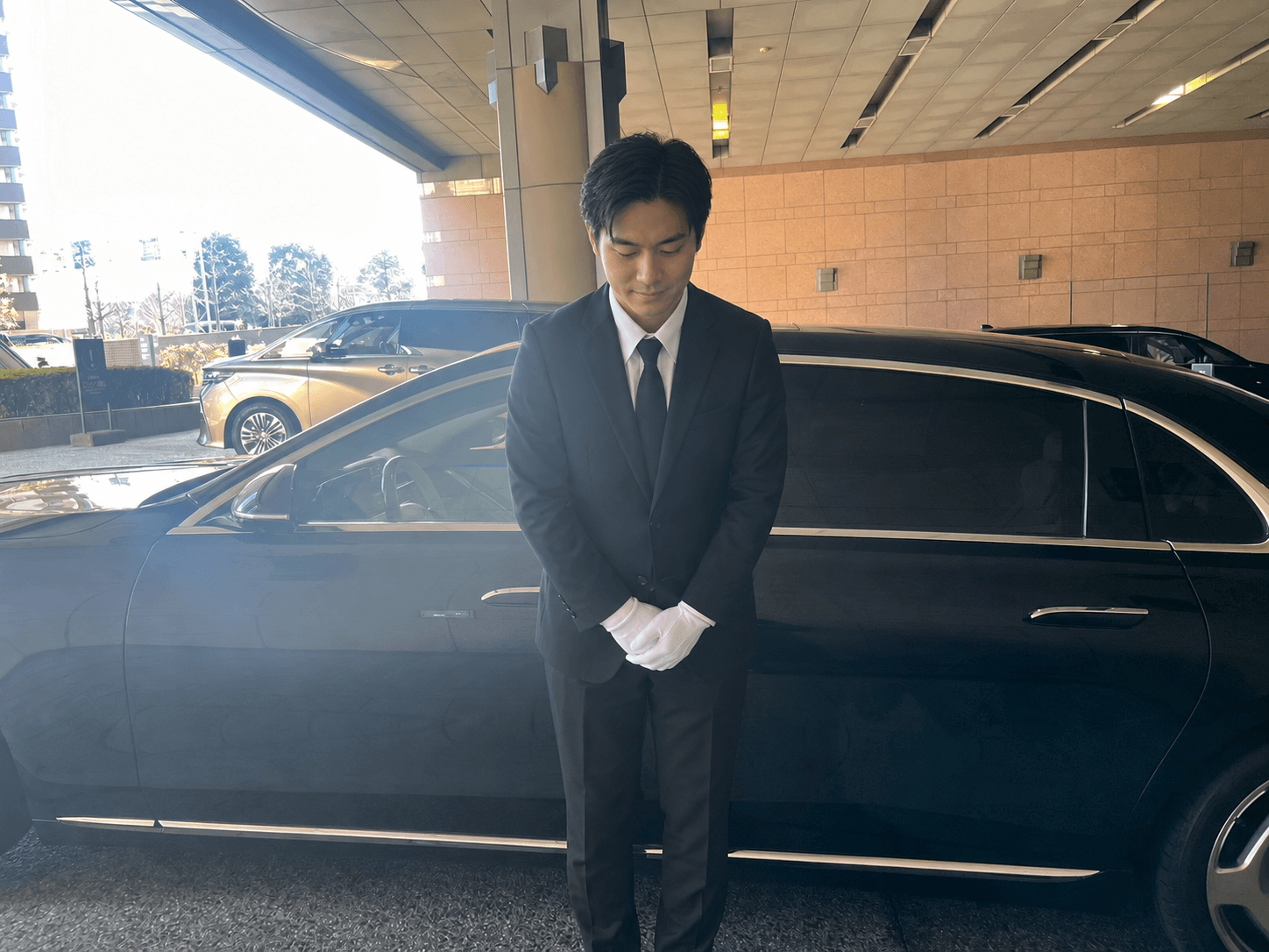 車両の前で丁寧にお辞儀をするドライバー