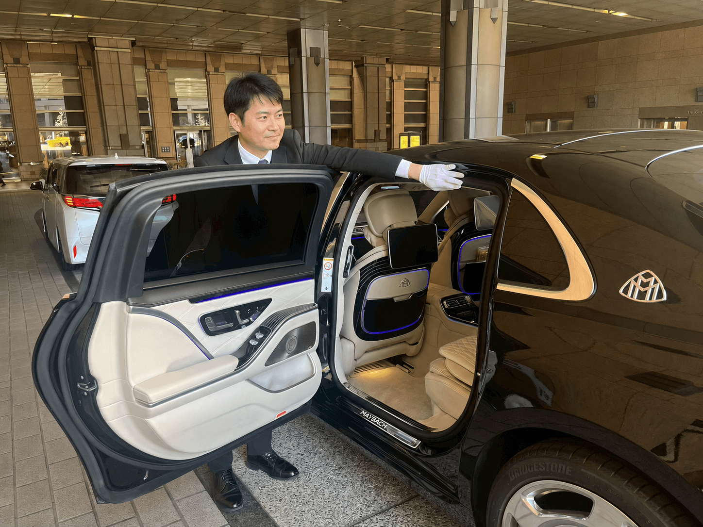 後部座席のドアを開けてお客様をお迎えするドライバー